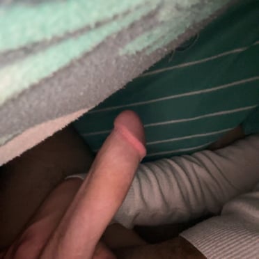 A beautiful, medium-sized, smooth-skinned dick peeks out from under the covers.