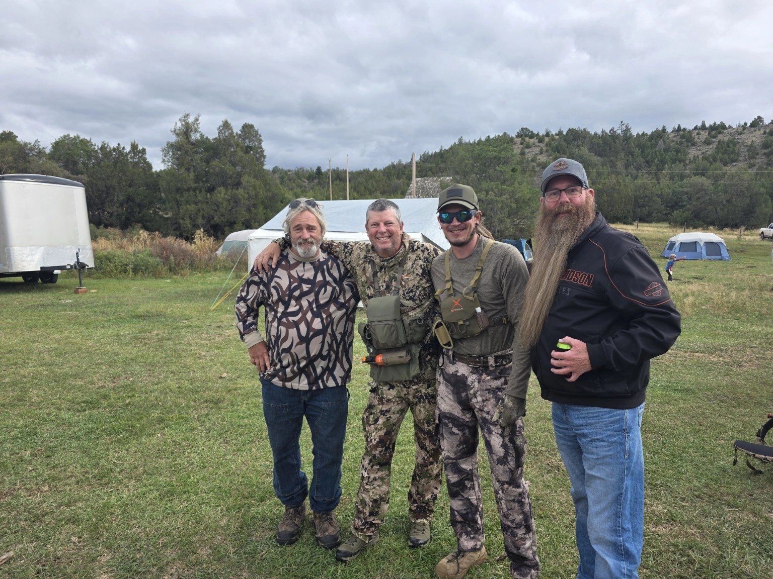 Four people together on the grass at camp