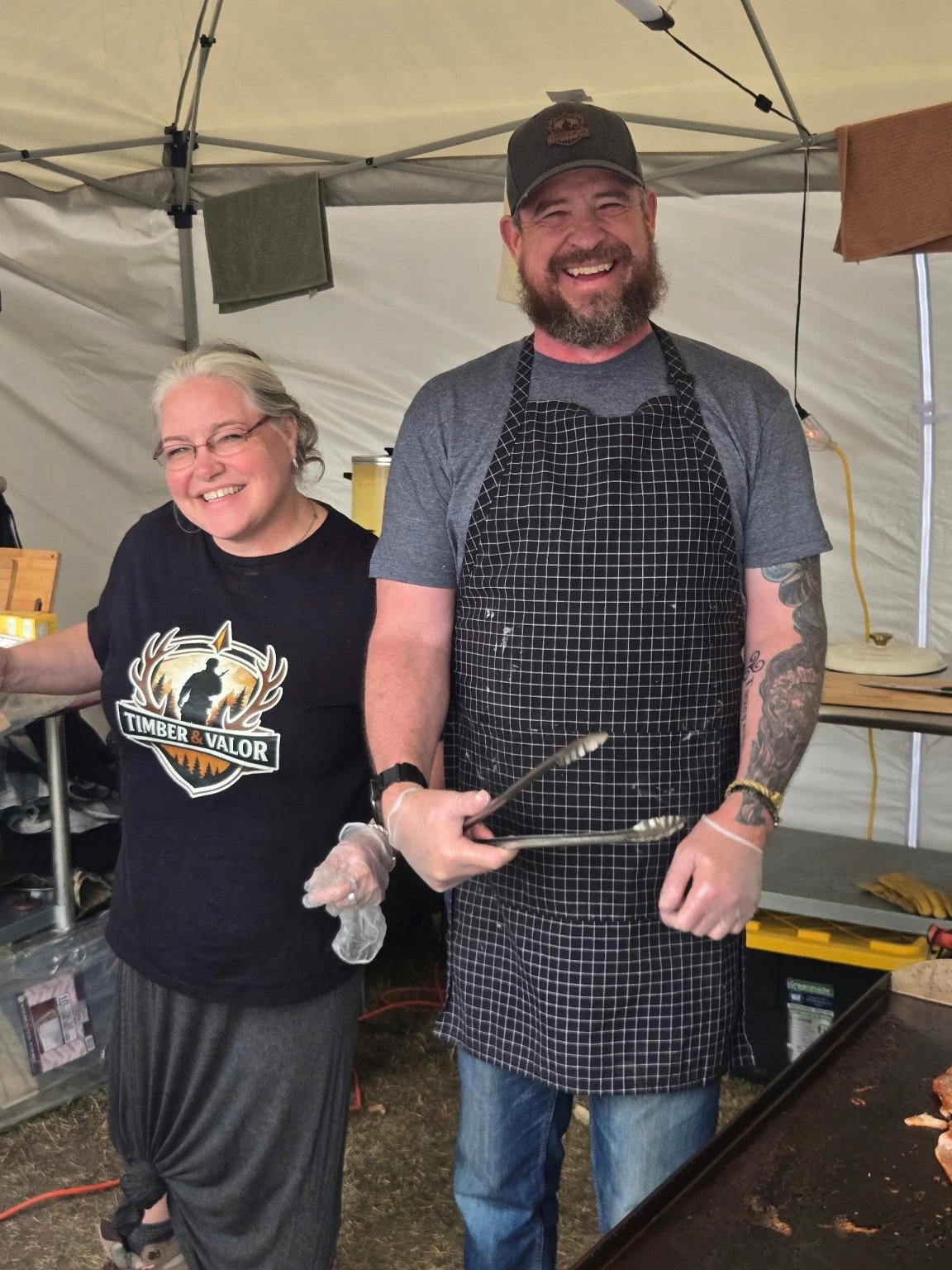 Two smiling cooks preparing food at camp