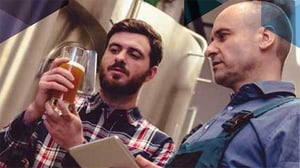 people talking looking at a beer in a manufacturing facility