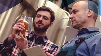 people talking looking at a beer in a manufacturing facility