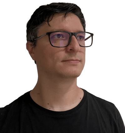 A person with glasses and short hair is looking thoughtfully to the side.