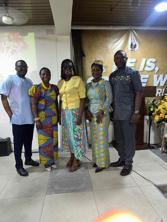 Five church members posing together in front of the pulpit and flowers on Mother’s Day