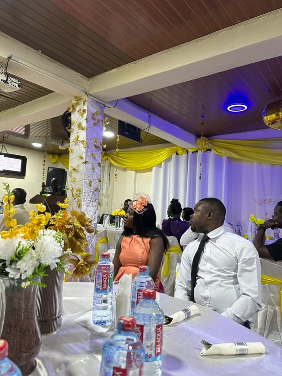 Guests seated at decorated tables during a church celebration in a hall dressed in yellow and white