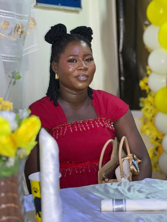 A woman in a red beaded dress seated at a table with yellow flowers