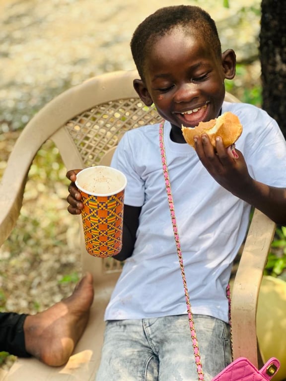 A laughing child enjoying bread and a hot drink