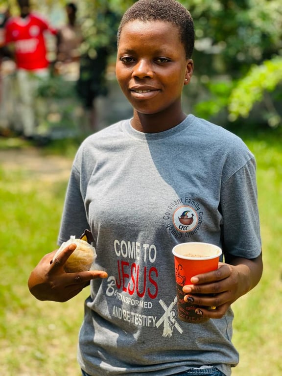 A young woman in a CFCC “Come to Jesus” T-shirt holding a snack and a cup