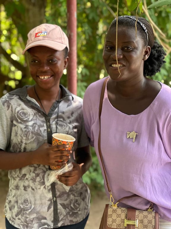 Two women smiling together under the trees with refreshments