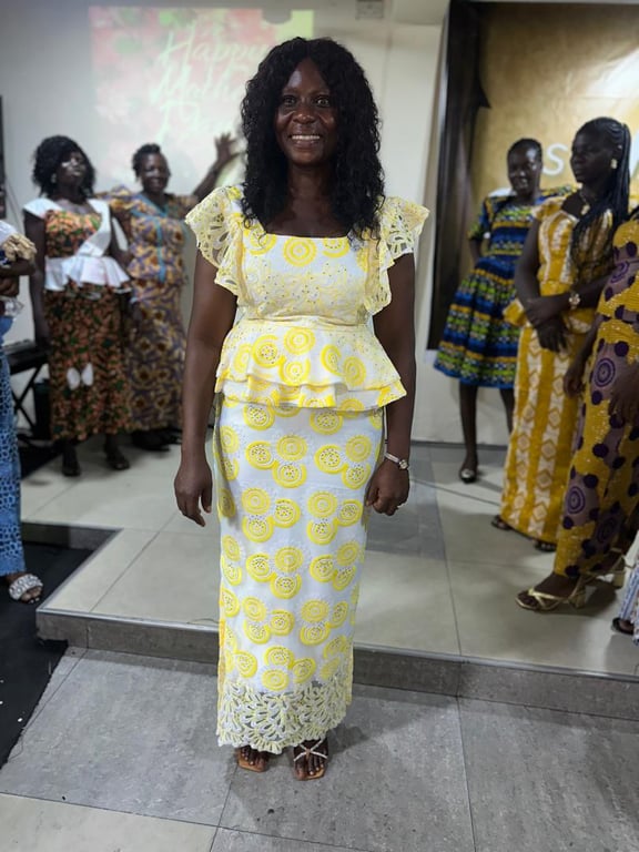 A smiling mother in a yellow and white lace outfit at the Mother’s Day celebration
