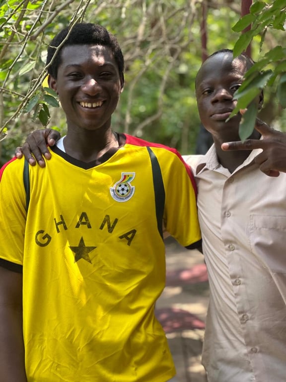 Two young men smiling together, one in a Ghana football jersey
