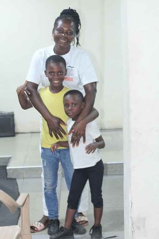 An adult standing with two children beside a light-coloured wall