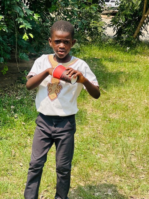 A boy holding a cup on the grass during the Love Feast