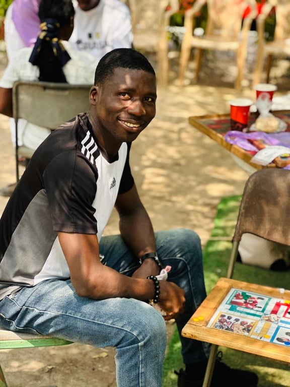 A church member smiling beside a ludo board during the Love Feast games