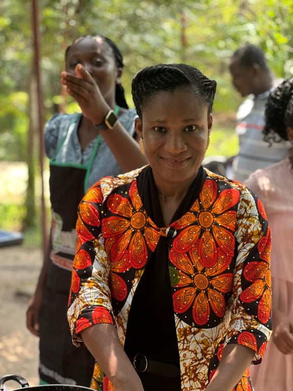 A smiling woman in a bright orange print outfit at the Love Feast