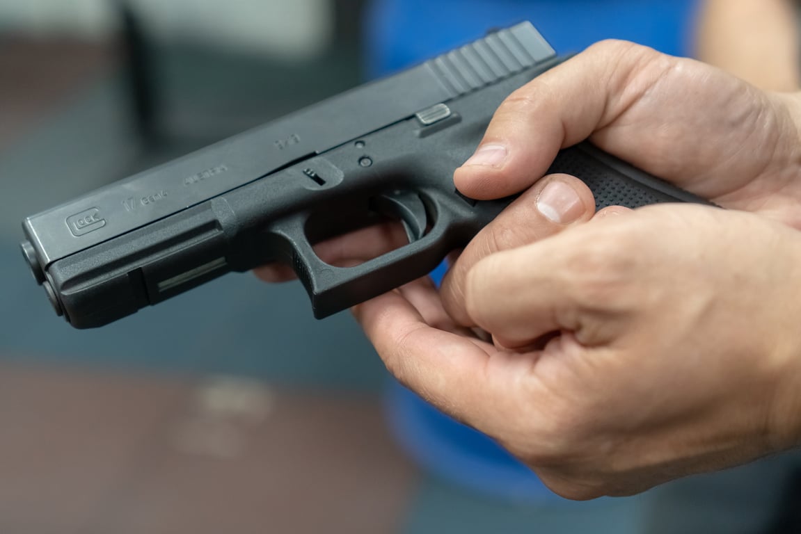A hand of man practicing firing using a Glock gun model at the shooting range.