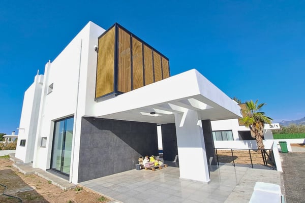 Side angle of the villa with wooden vertical cladding, floor-to-ceiling windows, and minimalist exterior lighting features.