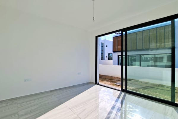 Bright secondary bedroom or study room with sliding doors leading to balconies and light neutral interior tones.