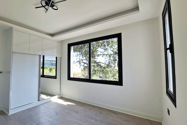 Guest bedroom with dual windows and open floor space.