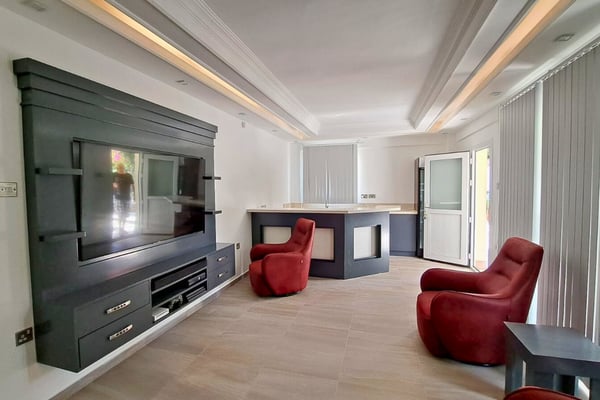 TV lounge with slate feature wall and red armchairs, combining bold design with cozy retreat for relaxing moments.