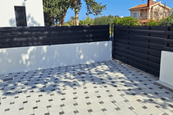 Patio section with modern geometric tiling and dark privacy fencing.