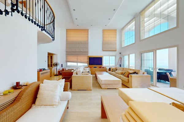 Expansive lounge area with a combination of soft and wooden furnishings, complemented by a view of the lush outdoor greenery.