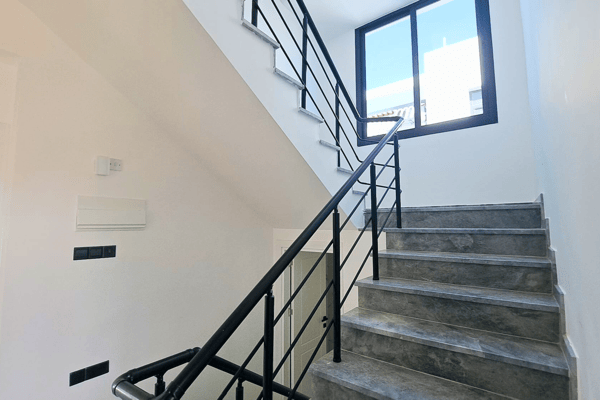 Main staircase with black metal railings and stone treads leading upstairs.