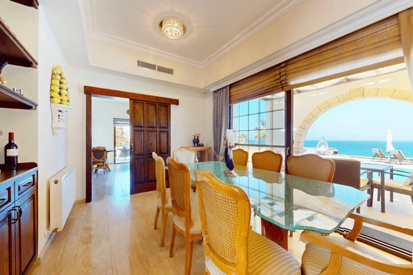 Dining space with arched windows, showcasing elegant wooden furniture and framed sea views.