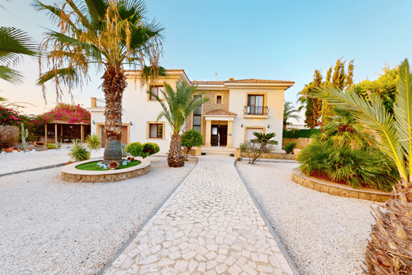 Cobbled courtyard with palms and frontal access to the villa’s dual wings, creating a grand entrance feel.