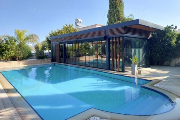 Villa’s elegant front façade with warm-colored walls, palm trees, and a paved driveway.