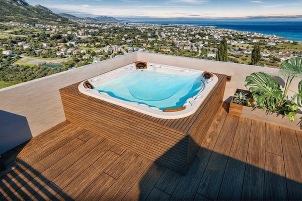Stylish rooftop space with ocean-facing seating, sleek glass barriers, and a patio umbrella shading the modern lounging area.