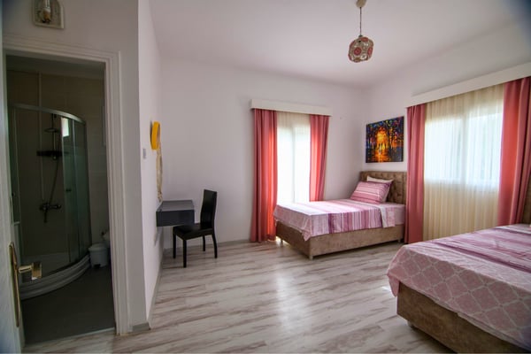 Guest bedroom with twin beds and soft tones offering a calm, comfortable atmosphere for visitors.