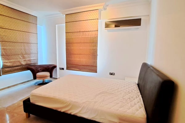 Guest room with warm wood tones and storage wall, offering understated comfort and modern functionality.