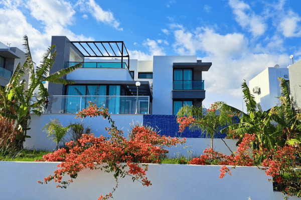 Wide rear shot of villa showcasing double-story architecture, vine-covered walls, and vibrant landscaped garden.
