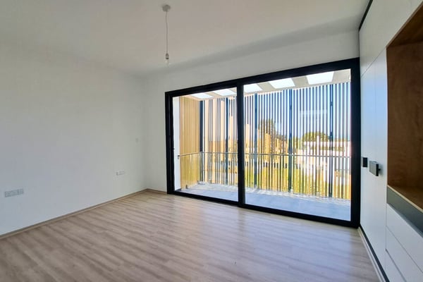 Guest or additional bedroom with built-in wardrobe, wood flooring, and large window enhancing brightness and comfort.