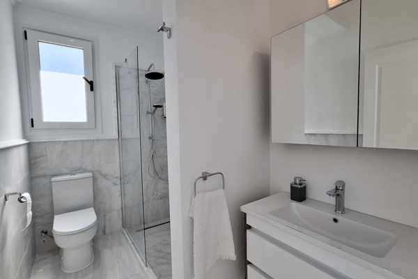 Compact bathroom with toilet and white cabinetry.
