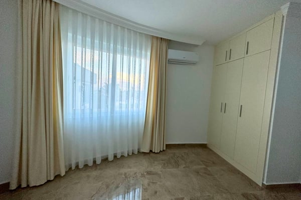 Second bedroom bathed in natural light, with simple furnishings and calm hues that inspire restful, modern living.