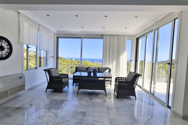 Dining area with rattan-style furniture and expansive windows.