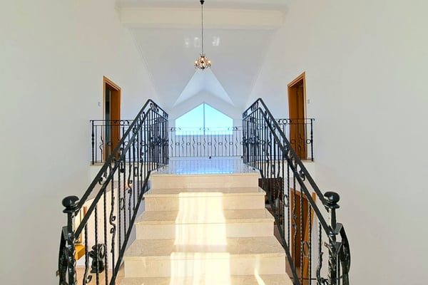 Cathedral window above stairwell, bringing in natural light and heightening the visual drama of the central hallway.