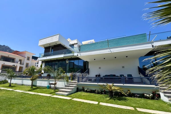 Ground-level view of a modern home with striking exterior accents, manicured lawns, and fluid indoor-outdoor architectural harmony.