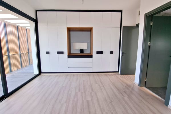 Spacious main bedroom with modern wardrobe, wood flooring, expansive windows, and contemporary design elements.