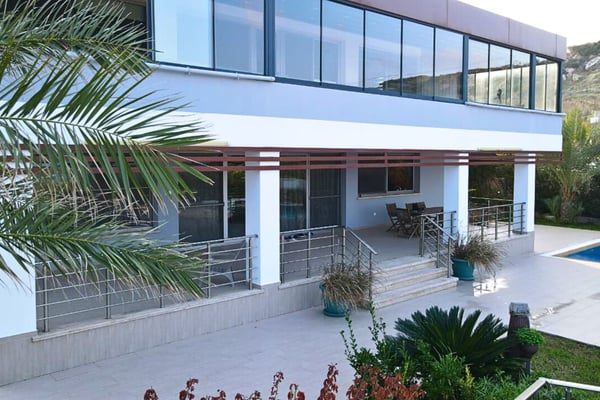 Upper-level balcony of a luxury sea-front villa in Esentepe, featuring glass railings, modern architecture, and uninterrupted sea views.