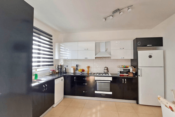 Modern kitchen with tall fridge, venetian blinds and layered lighting, balancing convenience with contemporary design.