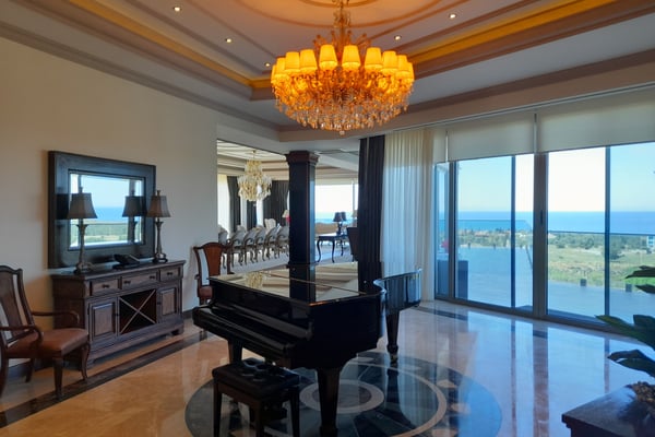 King-Size Bedroom with Ornate Ceiling Details – A refined bedroom with a king-size bed, an upholstered headboard, decorative ceiling moldings, stylish wood or tile flooring, and matching bedside tables.