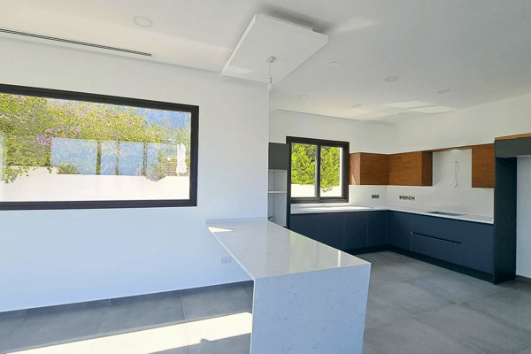 Open-plan kitchen and dining space with minimalist cabinetry and wide windows.