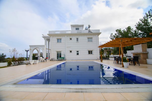 Rear view of luxurious villa featuring an expansive pool and stylish outdoor leisure spaces ideal for entertaining.