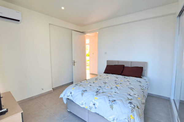 Stylish guest bedroom featuring a warm-toned frame and sunlit serenity through side-facing windows.