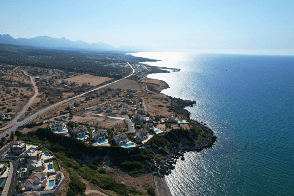 Drone shot capturing the stunning cliff-side position of the villa with the vast turquoise Mediterranean sprawling beyond.