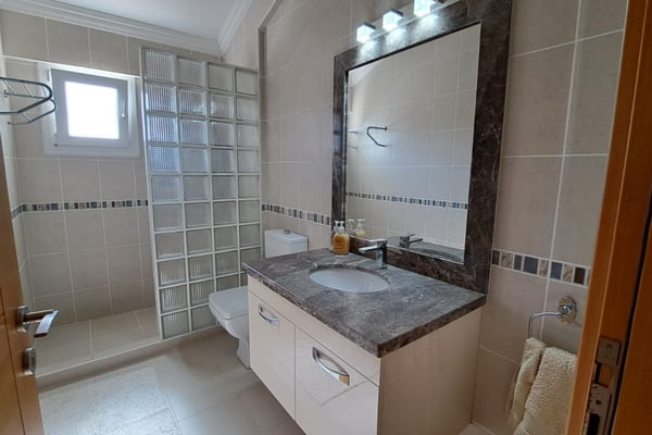 Minimalist shower room with glass enclosure, wall-hung fixtures and beige tiles offering sleek, modern appeal.