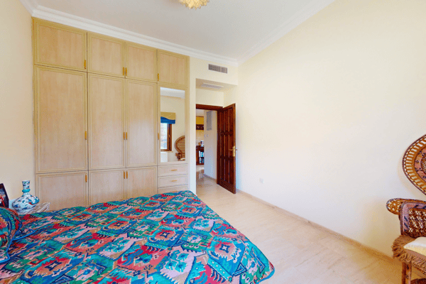 Bedroom with vibrant carpet, built-in wardrobes, and classic wooden furniture.