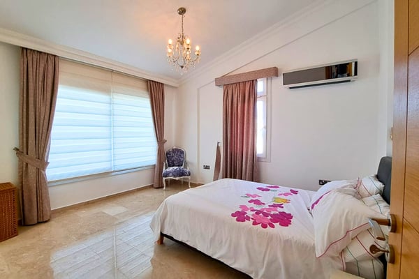 Master bedroom with crystal chandelier, terrace access and refined decor offering a luxurious private retreat.
